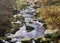 Rippling water in the riverbed of the Oker near Goslar, out of which round stones overgrown with moss protrude