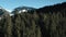 Rise over huge spruce trees behind which a view of the snow-capped mountains opens. High Tatras Mountains, Slovakia