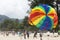 On the rise in the sky large parachute in the blue sky tropical beach. Two Chinese tourists flying on a parachute over the sea on