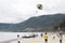 On the rise in the sky large parachute in the blue sky tropical beach. Two Chinese tourists flying on a parachute over the sea on