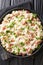 Risi e Bisi classic Italian comfort food of rice with peas and chunks of ham close up in a plate. Vertical top view