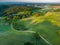 Rising Above the Beauty: Aerial View of Serene Green Pastures, Trees and Gravel Road During Sunrise with Drone