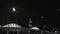 Rising moon behind a colorful illuminated modern bridge time lapse