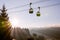 Rising sun over Seiser Alm plateau covered in morning haze and cable car cabins in the air