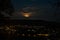 Rising super moon with clouds over cityscape