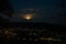 Rising super moon with clouds over cityscape