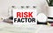 Risk factor words written on medical blue folder with patient files, pills and stethoscope on background