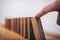 Risk and strategy in business, Close up of businessman hand gambling starting push wooden block on a line of domino