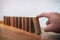 Risk and strategy in business, Close up of businessman hand gambling starting push wooden block on a line of domino