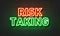 Risk taking neon sign on brick wall background.