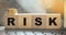 Risk Word On wooden Blocks Arranged Behind computer keyboard and stack of coins. Risky investment business concept