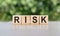 RISK word written on wooden blocks. The text is written in black letters and is reflected in the mirror surface of the table.