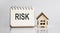 RISK words written in an office notebook with wooden house. Financial Business concept