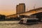 River boat with tourists in front of Nagatinsky Bridge with railroad and trains in Moscow during sunset