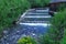 River cascading among green forest and wooden house