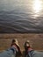 River embankment in the evening in clear weather. Kind of male legs in blue jeans and brown shoes