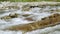 River flowing over rocks on sunny day, close up detail, rapid white water with blurred stones and grass background