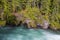 A river flows beneath forest-covered cliffs in Glacier National Park