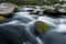 River flows among the stones. Blurry water.