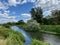 River Great Ouse, Houghton, Huntingdon, England. River under blue cloudy sky with green trees