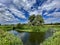 River Great Ouse, Houghton, Huntingdon, England. River under blue cloudy sky with green trees