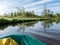 The river from a green fisherman`s rubber boat, calm river water with reflections and bright green vegetation on the shore