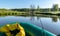 The river from a green fisherman`s rubber boat, calm river water with reflections and bright green vegetation on the shore