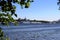 River, large cruise ships and small ships in the port, the view from the opposite Bank framed by tree branches