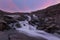 River of melt water from glacier and pink sunset background