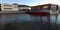 River and mountains. A red and black boat is moored to a concrete pier. Modern high-tech buildings in the background. 3d render