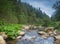 River in mountains with rocks, green grass on riverside. Mountain landscape, beautiful sky, clouds. Idea for outdoor activities,