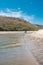 River mouth towards white sand beach with a forest background in the dry tropics and a young couple walking in the background