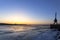 A river port crane stands on the banks of a frozen river in the evening