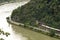 The river Rhine in western Germany flows between the hills covered with forest, visible freight train and traffic lights for ship