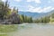 River with rock bluffs and pine forest with mountains and blue sky in summer