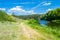 River Teteriv Teteriv. Field dirt road near the riverbed, overgrown with bushes and trees on the shore, with granite hill, fores