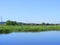 The river to the village with an old house . Summer rural landscape. Country, grass, river in Belarus