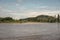 River water with horse, green trees, hills on blue sky