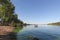 River water with horse, green trees, hills on sunny blue sky, nature. Riverscape, nature, ecology, environment