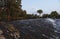 The river well with some reflections of trees on it and a small waterfall