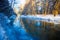 River in winter. Dappled sunlight streaming in mixed forest