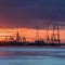 Riverbank with silhouettes of container terminal cranes during a sunset, Port of Antwerp, Belgium