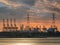 Riverbank with silhouettes of container terminal cranes during a sunset, Port of Antwerp, Belgium