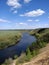 Riverbend in deep spring forestm with green trees on the bank of the river and sands under blue sky