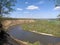 Riverbend in deep spring forestm with green trees on the bank of the river and sands under blue sky