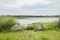 Riverside chained concrete flood pyramids in weeds on cloudy summer day