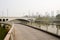 Riverside footbridge before arch bridge on urban fringe in sunny