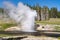 Riverside Geyser erupts in Yellowstone National Park, with a rainbow in Wyoming USA