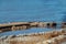 Riverside sidewalk trail undermined and broken after flood -parts propped up with rocks - surrounded by debris and trash