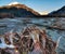 Riverside tree stump with mountains at sunrise